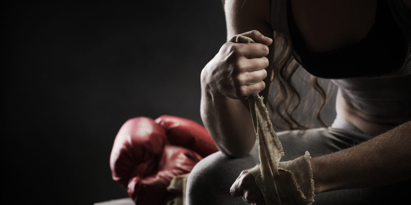 Woman boxer wrapping bandage around hand prior to game.